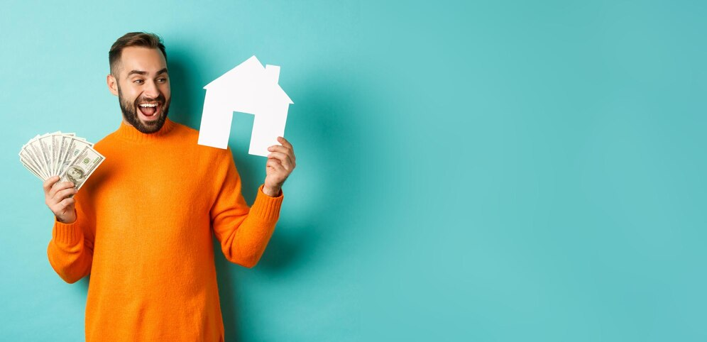 Homem segurando uma casa de papel com uma mão e cédulas de dinheiro com a outra, ilustrando o conceito de financiamento de imóveis usando o FGTS para aquisição de casa própria.